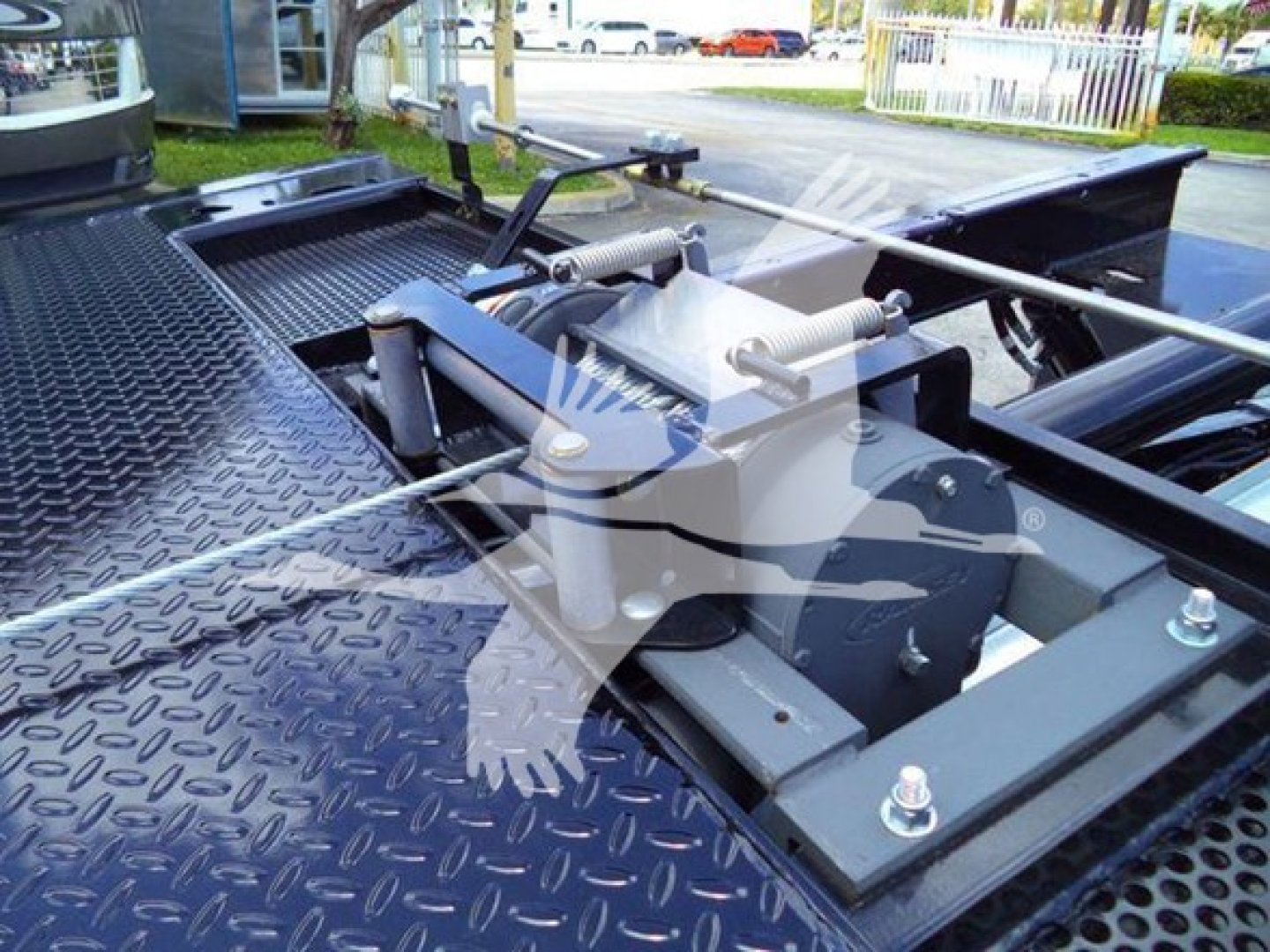 Tractor-trailer rollback system mounted on a metal diamond plate bed showing hydraulic winch, pins, and linkage in a Chevrolet Silverado 6500HD rollback truck.