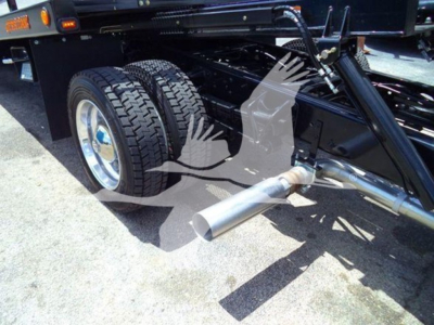 Truck chassis and exhaust system of a 2023 Chevrolet Silverado 6500Hd rollback showing rear dual wheels and tailpipe.
