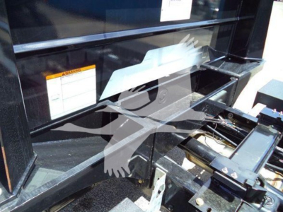Truck component close-up showing hydraulic lines and steel frame in a rollback truck bay.