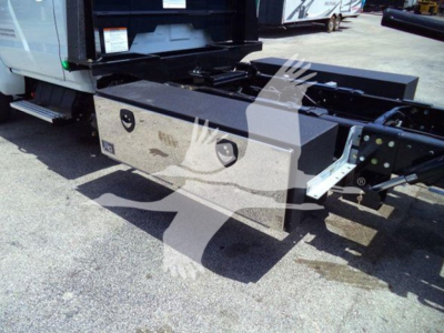 Toolbox/storage box mounted behind the cab of a Silverado rollback truck showing a metallic rectangular tool chest with two circular access ports and a black chassis.