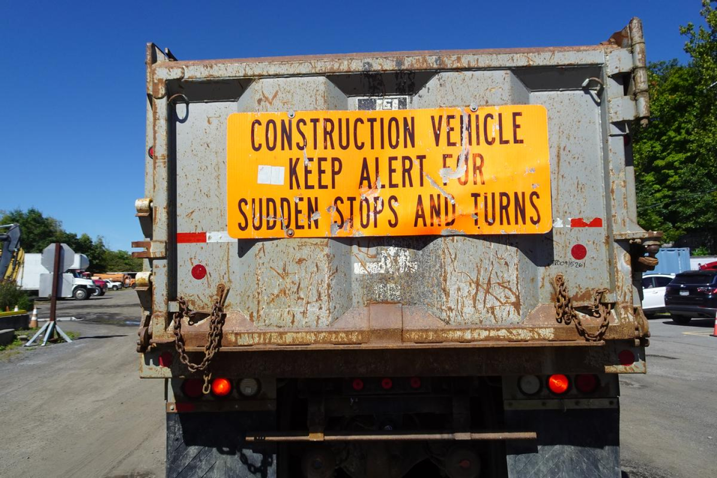 Rear view of a used 1986 Peterbilt 359 dump truck with a bright orange construction warning sign on the tailgate.
