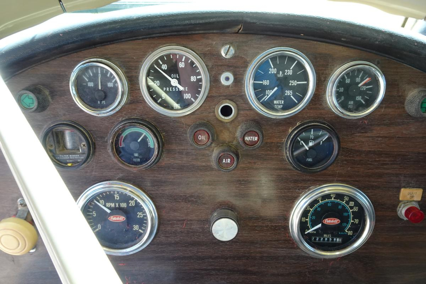 Truck dashboard showing multiple round gauges with wood-grain panel, including oil pressure, water temperature, voltage, and fuel gauges in Pandemonium style instrument cluster.