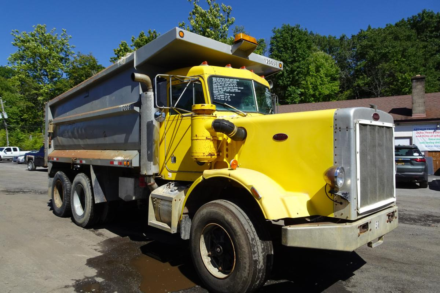 Peterbilt 359 dump truck in-service showing yellow cab and gray dump body with large grille and dual rear axles.