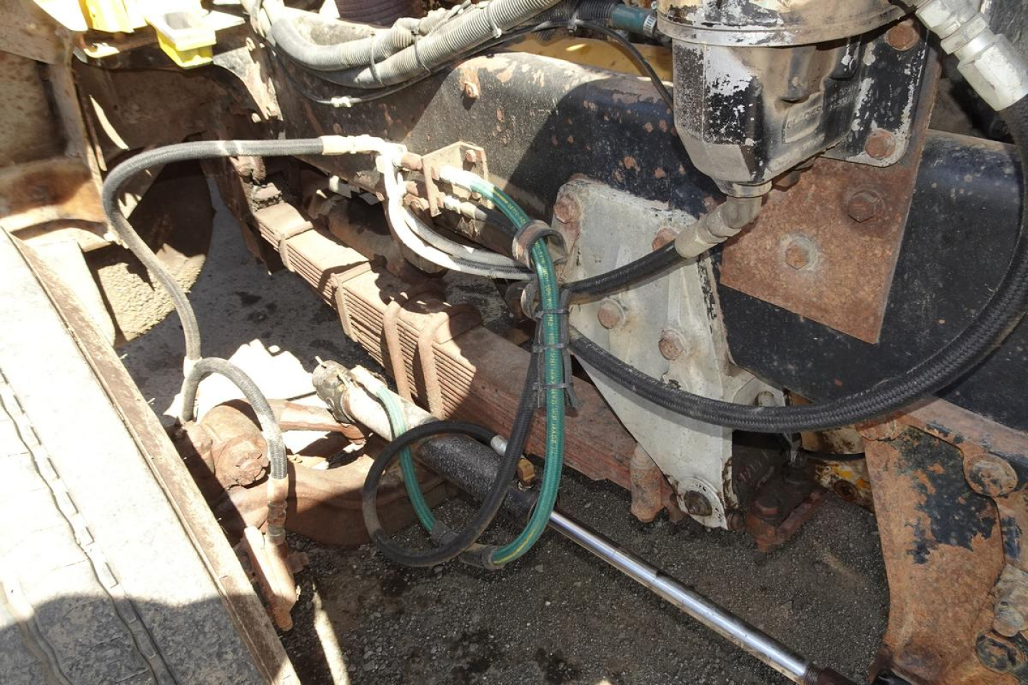 Engine bay view with wiring, hoses, and metal brackets in a Peterbilt 359 dump truck; visible components include cables, green hoses, and rusted metal surfaces.