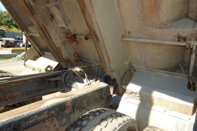 Dump truck bed with hydraulic ram and metal framework, showing wheel and undercarriage of a 1986 Peterbilt 359.