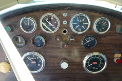 Truck dashboard showing multiple round gauges with wood-grain panel, including oil pressure, water temperature, voltage, and fuel gauges in Pandemonium style instrument cluster.