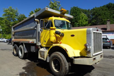 Peterbilt 359 dump truck in-service showing yellow cab and gray dump body with large grille and dual rear axles.