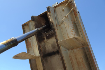 Dump truck bed hinge and hydraulic piston from a Peterbilt 359 dump truck showing metal bed lift mechanism.
