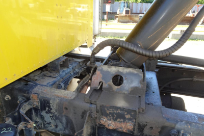 Peterbilt 359 dump truck chassis with hydraulic hoses and frame components visible under yellow cab, showing wear and dirt.