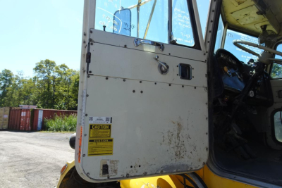 Truck cab door and interior of a dump truck. Visible yellow caution label on door, VIN/serial plate area not fully legible.