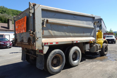 Peterbilt 359 dump truck in-service rear angle showing dump bed and rear wheels, with orange sign on tailgate.