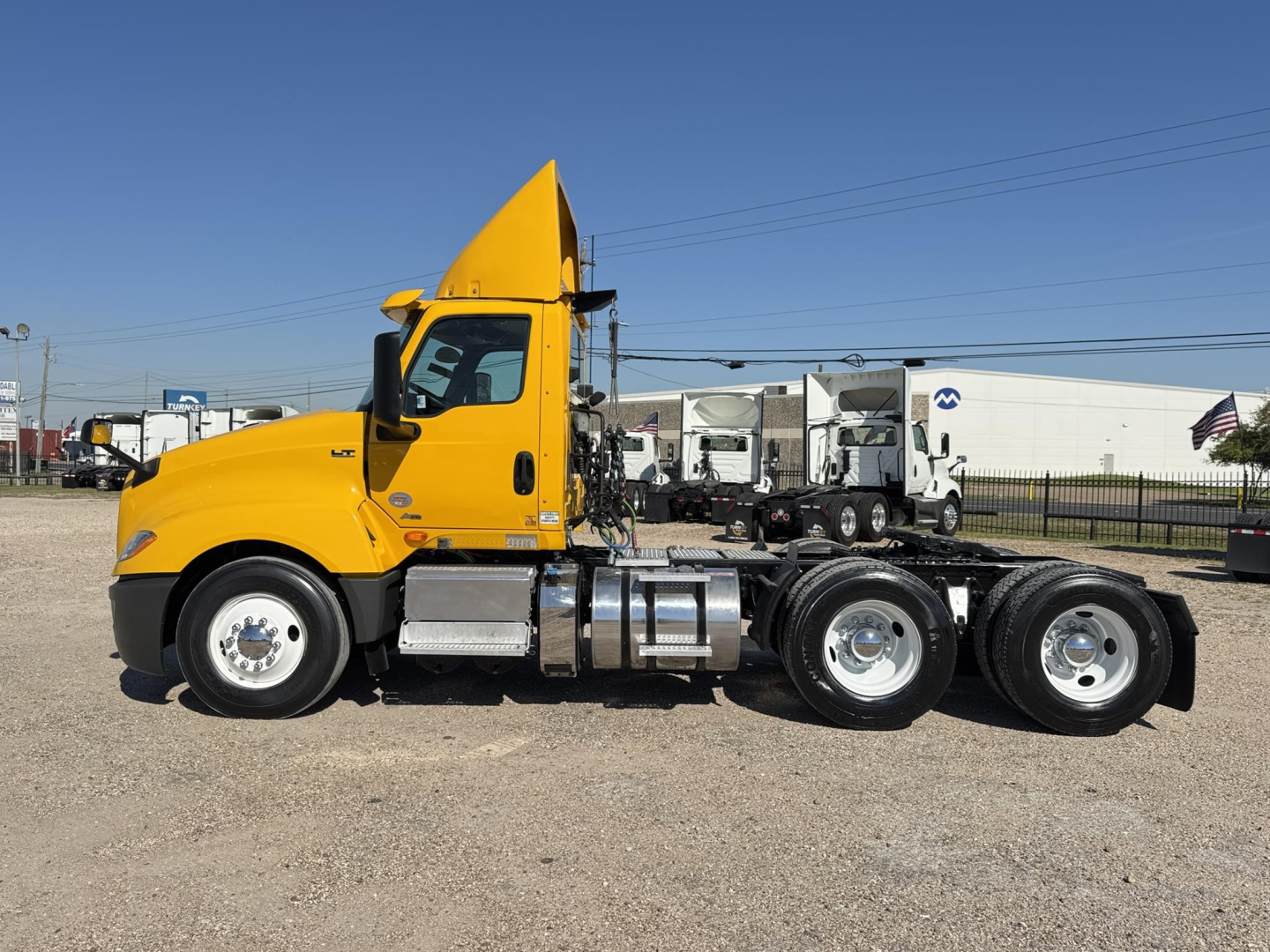 Side view of a yellow 2019 International LT conventional day cab truck showing a long chassis with dual rear axles and chrome fuel tanks.