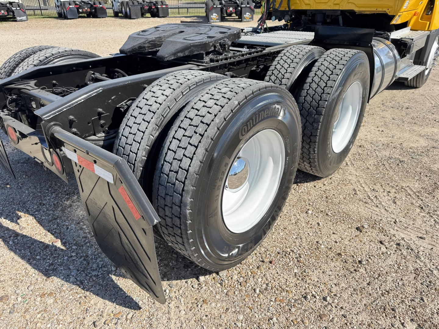 Triple-axle tractor rear showing dual rear tires with Continental tires and fender mud flaps.