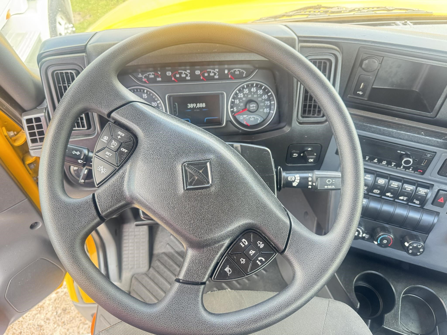 Interior of a 2019 International LT truck cab showing steering wheel with control buttons, dashboard gauges, and center console.
