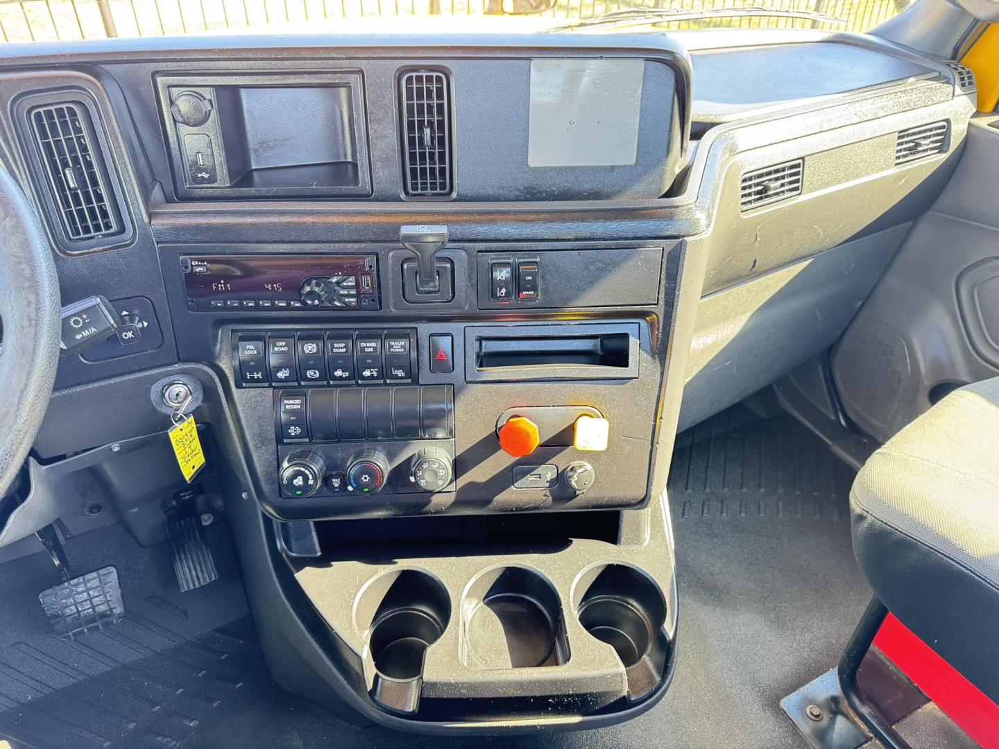 Cab interior of a 2019 International LT truck showing dashboard controls, radio, climate knobs, USB? not visible, and cup holders.