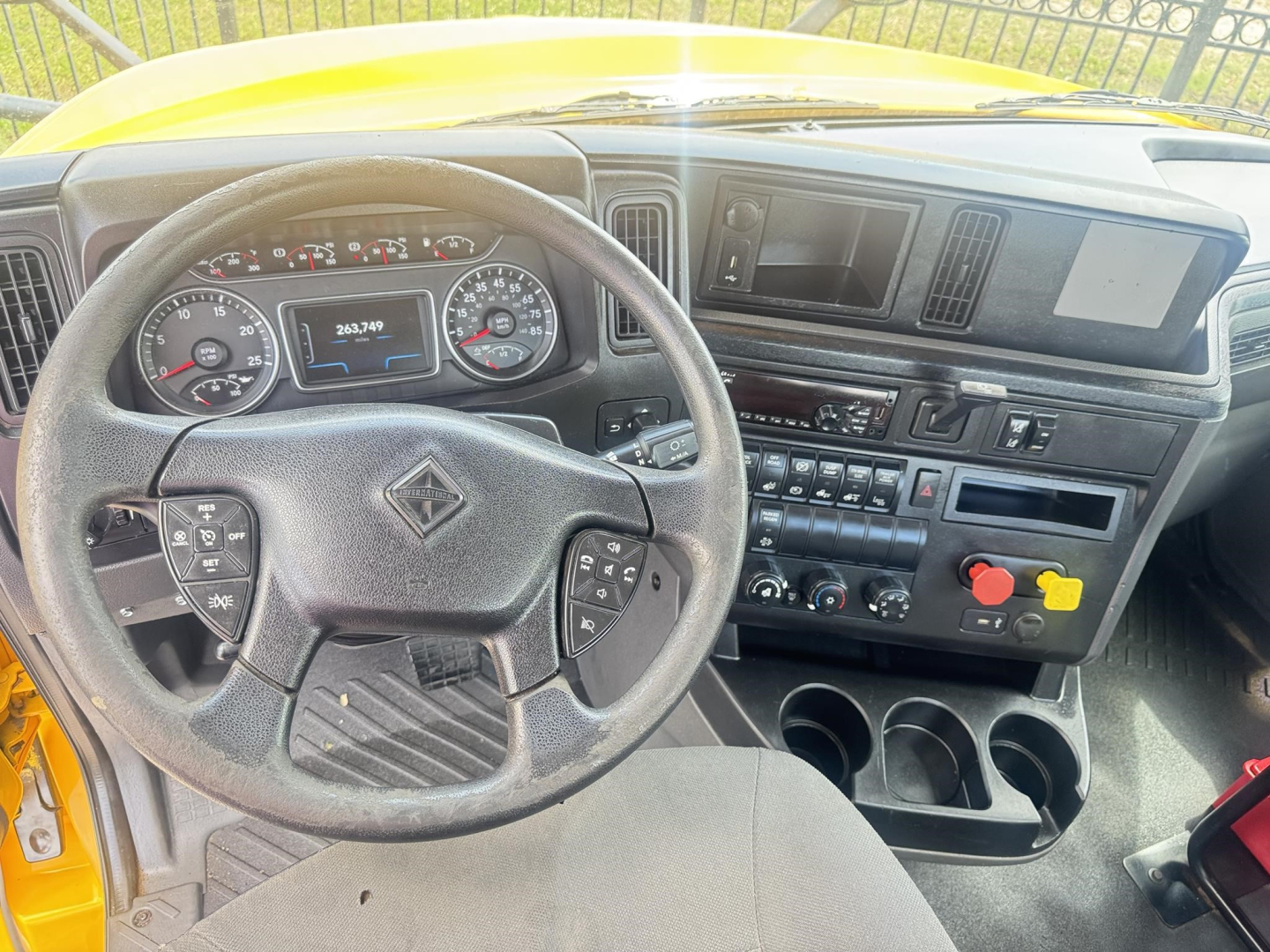 Dashboard and steering wheel view in 2019 International LT cab with center display, multiple controls, and cup holders.