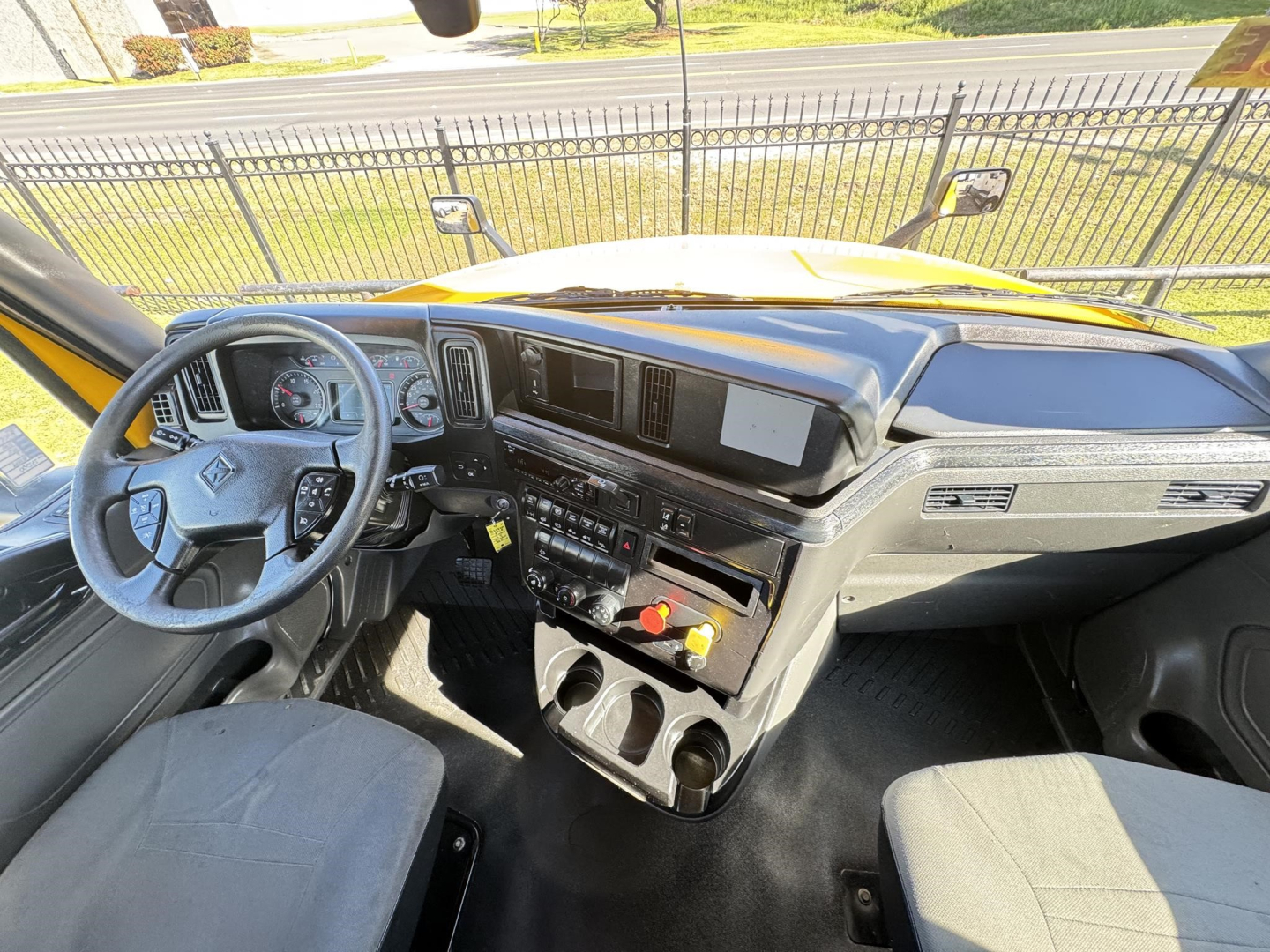 Cab interior of a 2019 International LT daycab showing steering wheel, dashboard, center console with controls, and cup holders.
