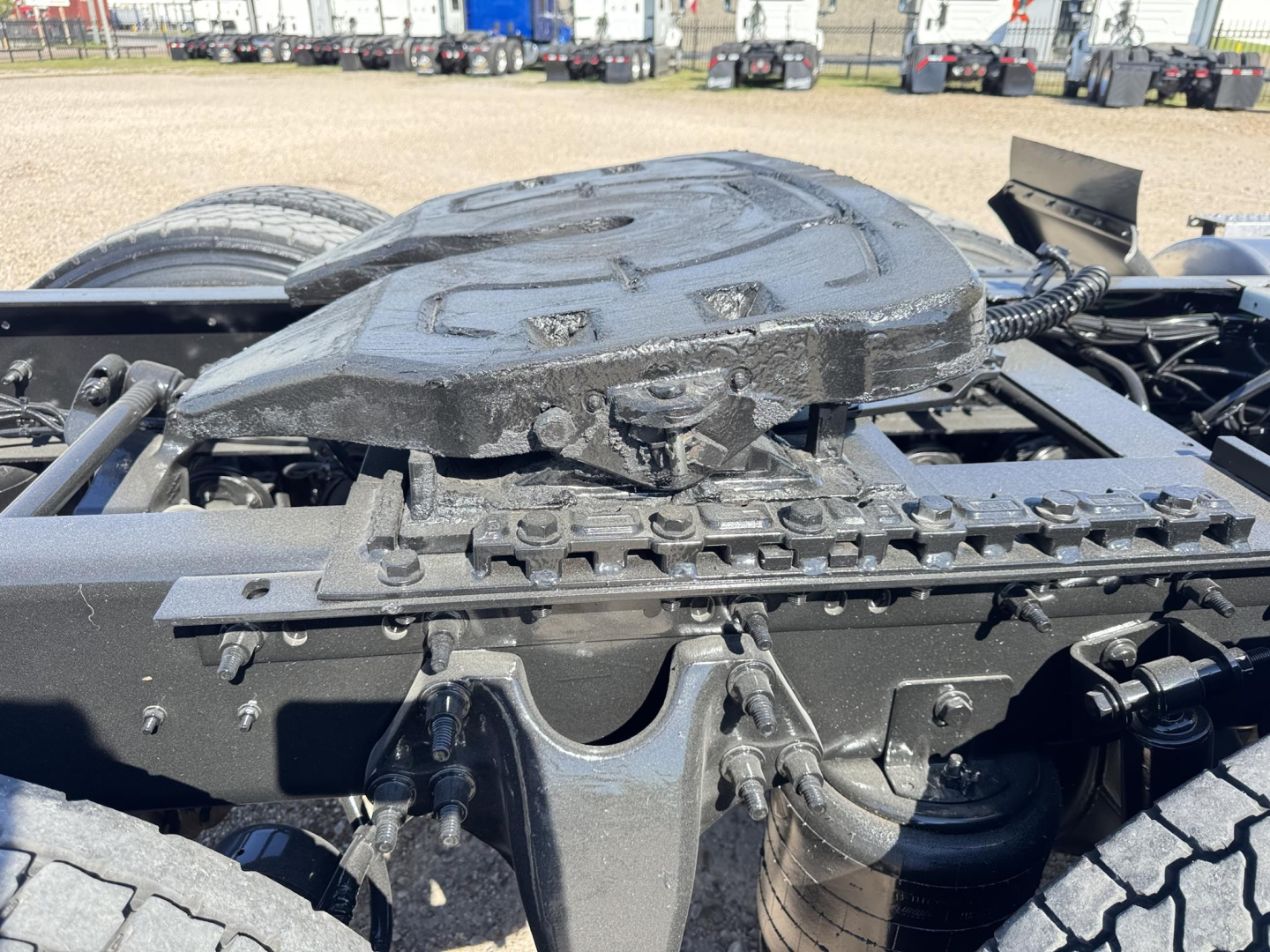 Tractor-trailer chassis showing fifth wheel and drive components with matching black metal frame and suspension parts.
