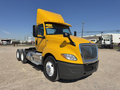 Truck cab of a yellow 2019 International LT conventional daycab, front-left view showing chrome grille, black bumper, side mirrors, and attached dual rear axles.