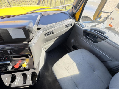 Cab interior of a 2019 International LT truck showing steering wheel, dashboard, and passenger seat with control panel and cupholders.