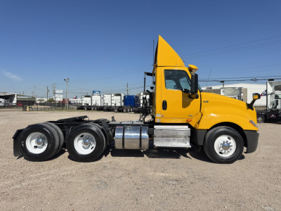 Truck side view showing 2019 International LT conventional daycab, yellow cab, dual rear axles, chrome fuel tanks, and fifth wheel in a lot.