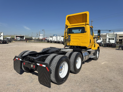 Truck cab and chassis showing fifth wheel area and dual rear axles, yellow International LT daycab with black underside components and white wheels, side view from rear-left.