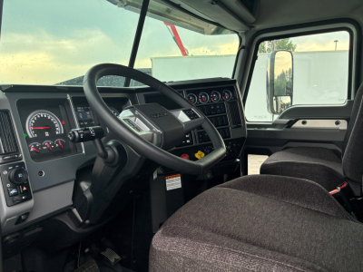Mack PI64 cab interior showing steering wheel, dashboard gauges, and driver seat.