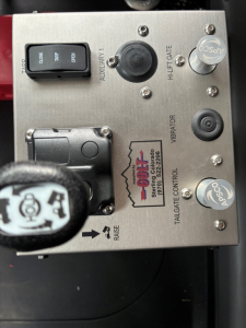 Mack PI64 control panel with switches and labels including AUXILIARY, TILT/TAILGATE, VIBRATOR, PTO, and a circular knob showing ASCO and APD logos, with wiring and a lever in view.