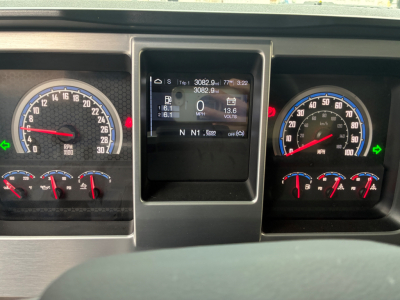 Dashboard of 2026 Mack PI64 showing instrument cluster with speedometer, tachometer, and central digital display. Visible texts include RPM gauges, gear indicators N, D, and digital readouts; multiple small indicators and warning lights.