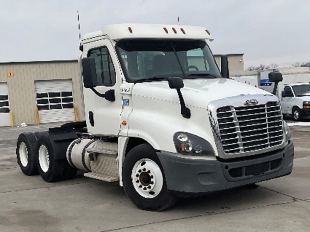Freightliner Cascadia125 conventional daycab truck front-left view showing dual rear axles, white cab, prominent grille, and large side mirrors.