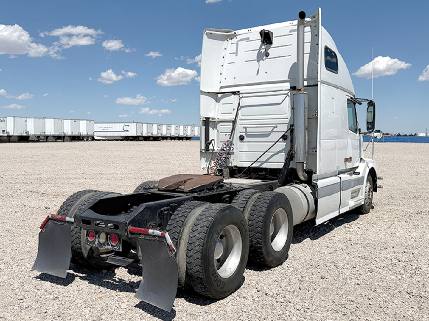 Volvo VNL 670 sleeper cab truck rear/side view showing fifth wheel and dual rear axles in a gravel lot.