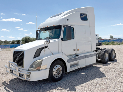 Volvo VNL 670 semi truck in a gravel lot, front view with sleeper cab, six wheels visible, no text readable on the truck exterior.