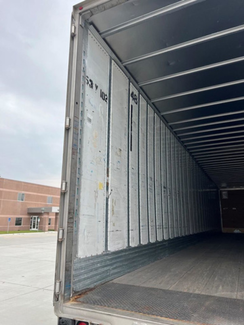 Interior of a used 2014 utility van trailer showing empty cargo area with metal side walls and roof ribs; visible markings '4E' and 'COMPANY' on wall; open rear entry