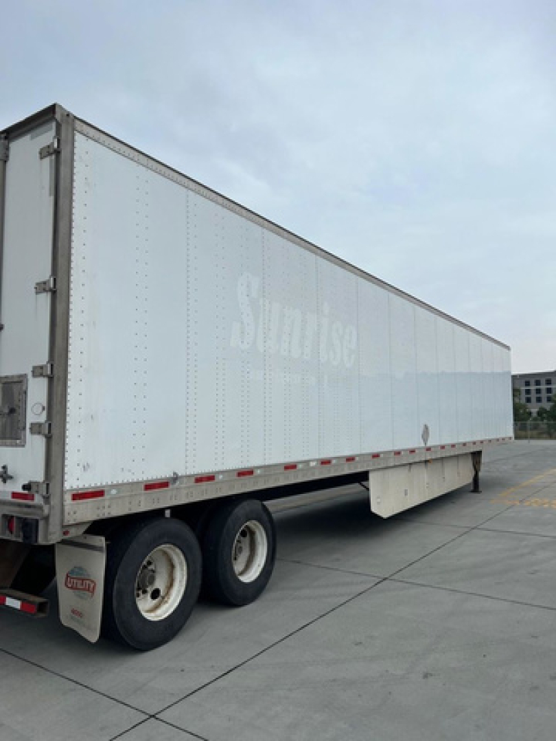 Trailer side view showing SUTLIUSE/SwiftGreen logo faded on white trailer with dual rear wheels and mud flaps.