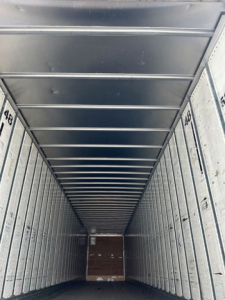 Van trailer interior showing longitudinal corrugated walls and a brown wood floor with numbered rows (48) along the sides.