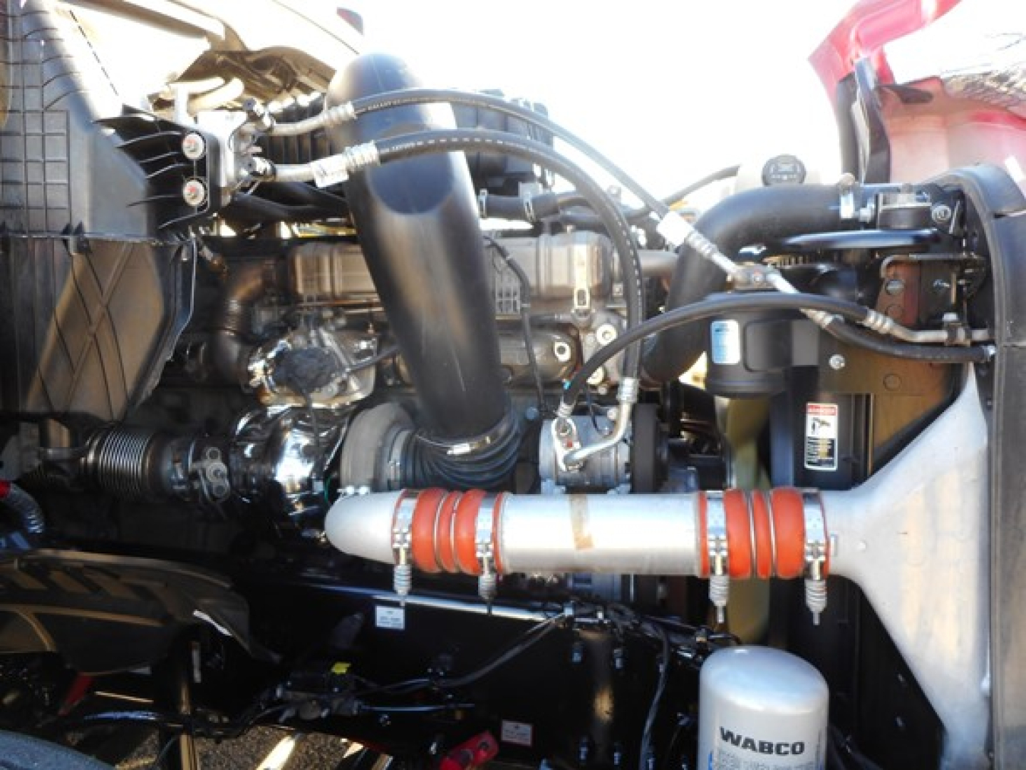Freightliner Cascadia engine bay showing turbocharger, hoses, radiator, and WABCO air dryer in the foreground.
