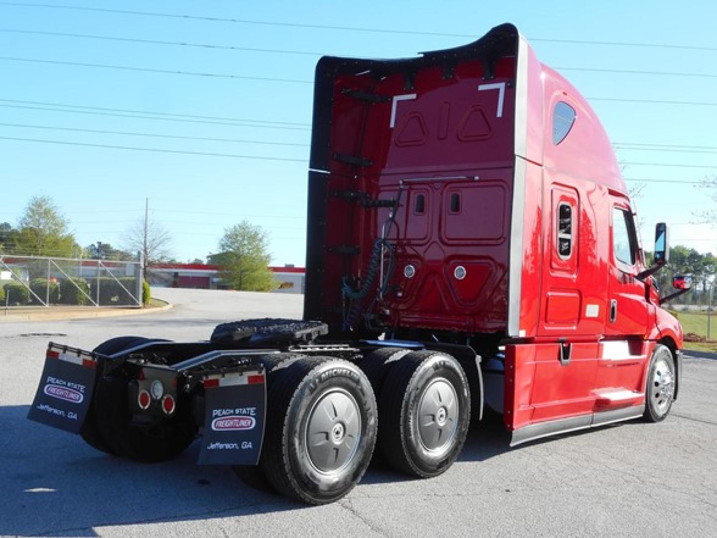 Freightliner Cascadia 126 sleeper tractor rear-left view showing red cab and dual rear axles.