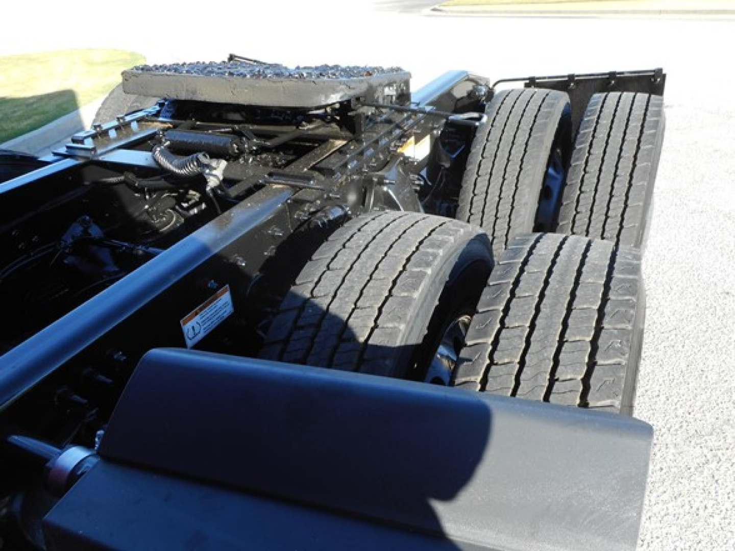 Freightliner Cascadia 126 chassis rear view showing twin rear axles and suspension components with tires and frame.