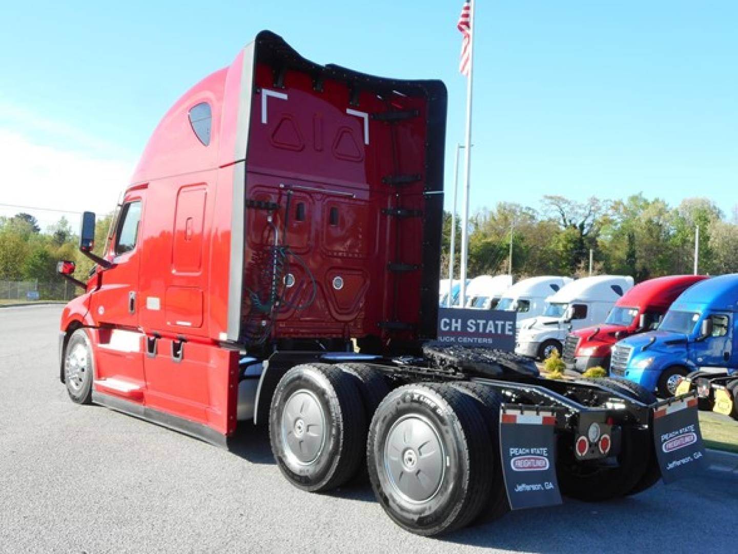 Cab view of a red Freightliner Cascadia 126 truck with sleeper, rear wheels visible, showing fifth wheel and chassis.