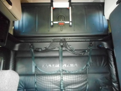 Cab interior of a Freightliner Cascadia 126 sleeper showing cargo area with net system and storage compartments.