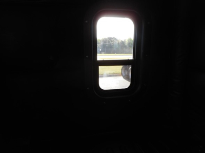 Dark interior window view with bright outside scene; small rectangular rear window with rounded corners