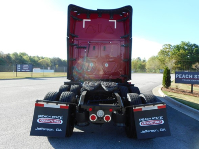 Rear view of a Freightliner Cascadia 126 tractor showing the back of the cab and dual rear wheels with mud flaps reading Peach State Freightliner Jefferson, GA.