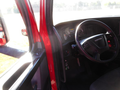 Cab interior of a red Freightliner Cascadia truck showing steering wheel and dashboard view