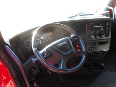 Freightliner Cascadia truck cab interior with steering wheel and dashboard controls visible.
