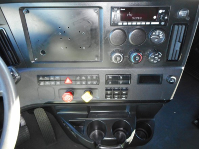 Dashboard of a Freightliner Cascadia truck showing radio, climate controls, hazard button, and two cup holders.