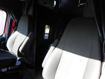 Freightliner Cascadia truck interior showing driver seat and passenger seat with cabin entry in background.