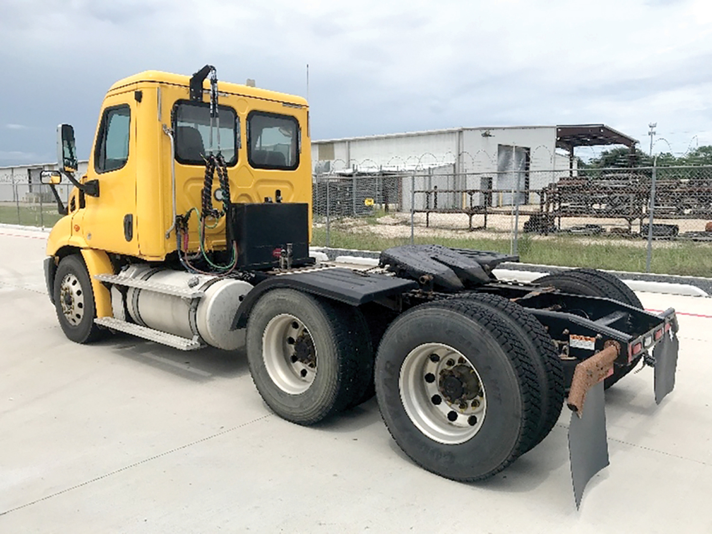 Truck side view of a yellow Freightliner Cascadia 113 daycab with dual rear axles and chassis, no trailer attached.
