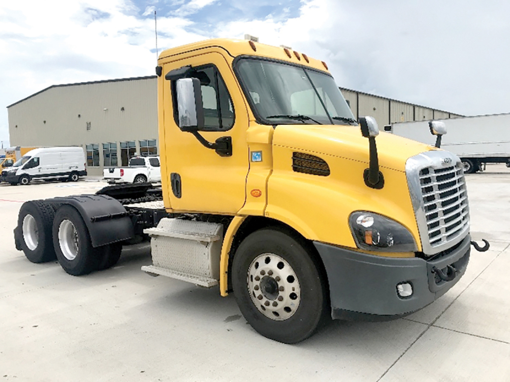 Truck cab view showing 2019 Freightliner Cascadia113 daycab with yellow paint, front grille, and dual rear axles.