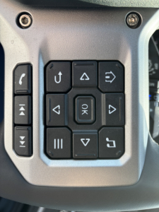 Driver steering wheel cluster with multiple control buttons for Mack AN64T truck; focus on keypad and left stalks.