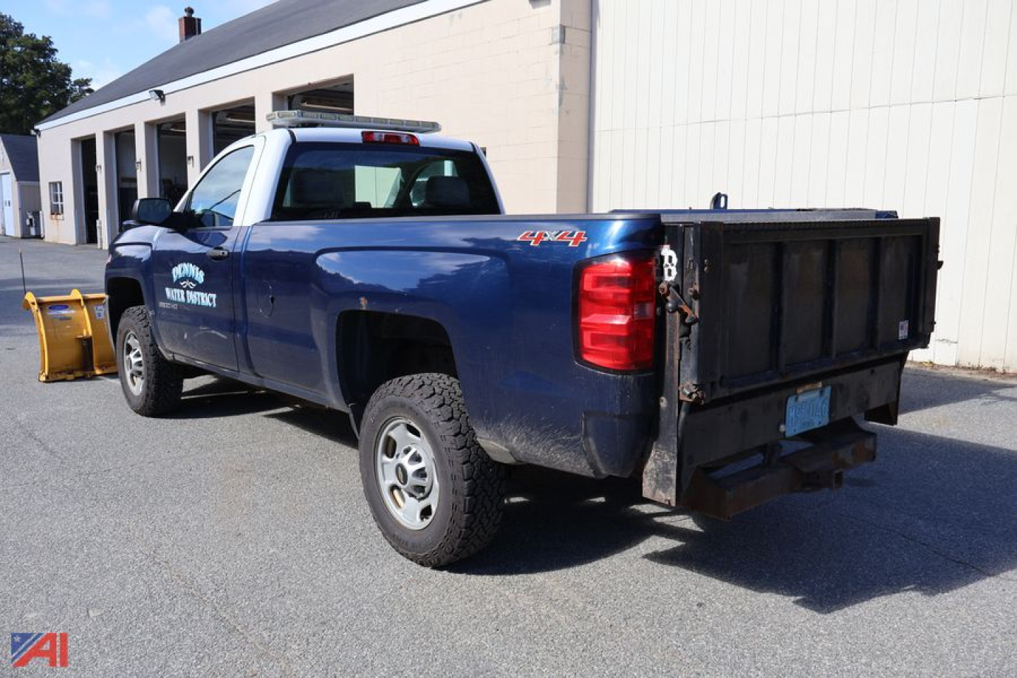 Chevrolet Silverado 2500 pickup truck in blue with utility bed, side logo, 4x4 badge, and snow plow attachment visible.